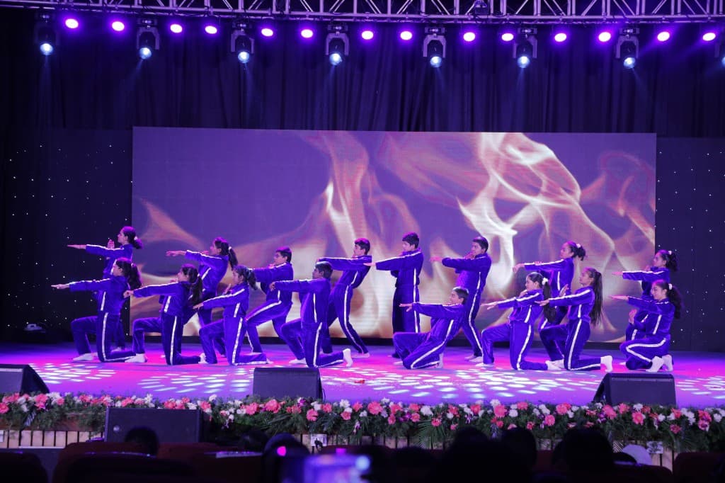 Students performing a group dance in purple on stage at Lawrence High School