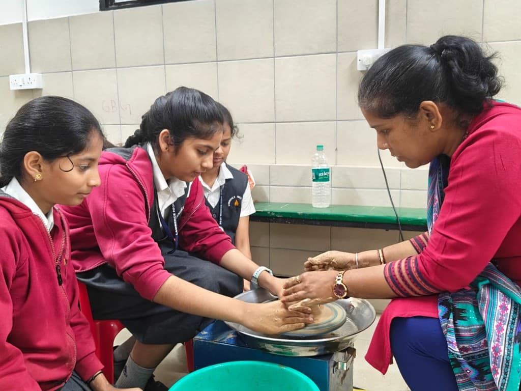 Students learning pottery with a teacher at Lawrence High School