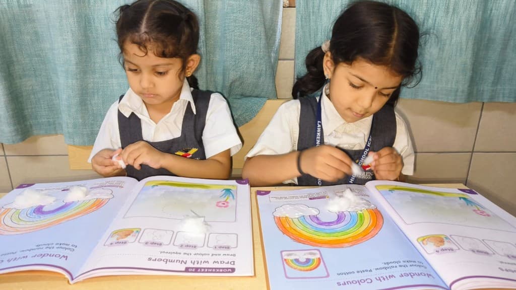 Kindergarten children working on colour and number worksheets at Lawrence High School