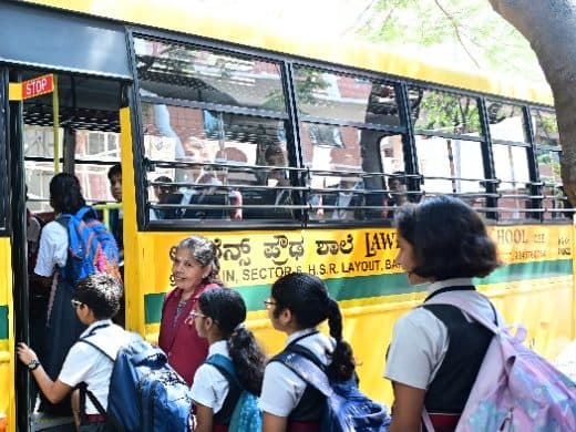 Students and a staff member beside a Lawrence High School bus